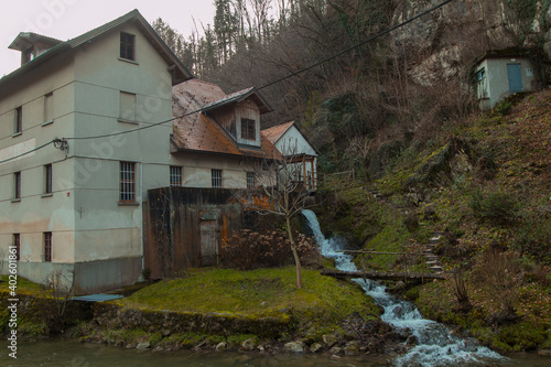 Old mill on a water next to a hill. Romantic setting for a water mill. © Anze