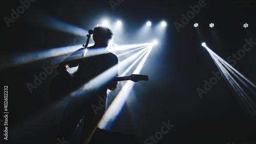 Silhouette of guitar player performinf on concert stage. Dark background, smoke, concert  spotlights