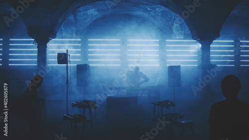 DJ playing on party under arch in ancient abandoned building 