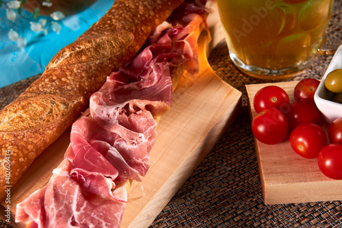 Cured ham sandwich also knows as Bocadillo de jamon serrano with food garnish of tomatoes and olives and a delicious beer. photo