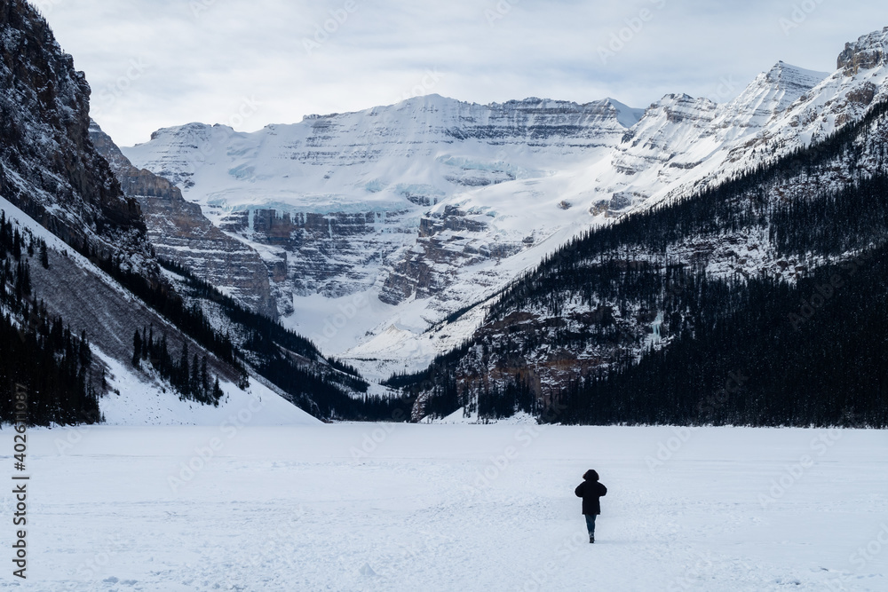 Back view of a man walking alone on the frozen Lake Louise, Canada