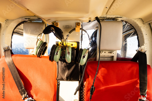 View inside a helicopter's passenger compartment with safety belts and headsets