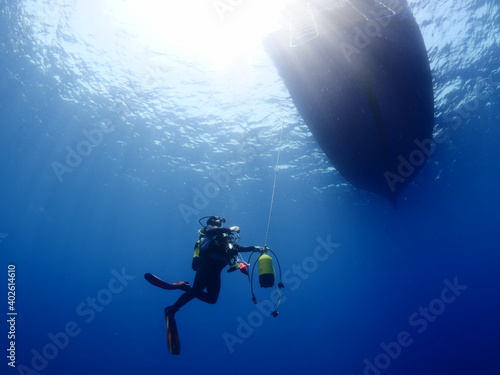 scuba diver underwater with boat and sun shine beam and rays safety stop
