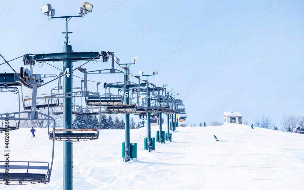 People are having fun in downhill skiing and snowboarding, panorama of ski lift
