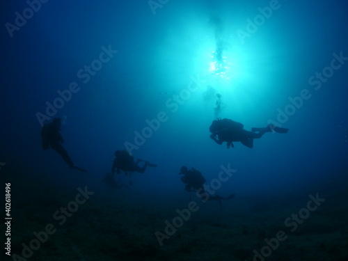 silhouette  scuba divers sun beam shine rays underwater lady woman diver relaxing blue ocean scenery of person © underocean