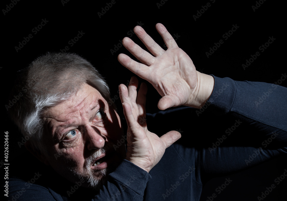 Fototapeta premium Ein älterer Mann wird von starkem Licht geblendet, er versucht sich mit den Händen zu schützen