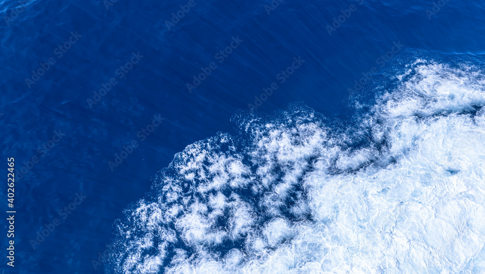 Top deck of Cruise Ship view  wake and rough deep blue and turquoise  pacific ocean  with white foam texture background.