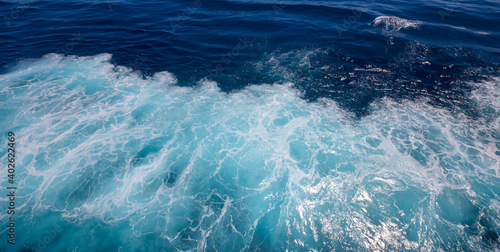 Top deck of Cruise Ship view wake and rough deep blue and turquoise pacific ocean with white foam texture background.