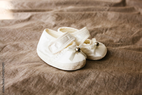 White baby shoes on a brown background. Shoes for a newborn or baby.