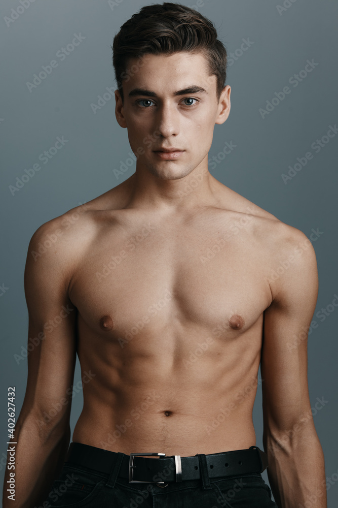 Portrait of a man with a naked torso on a gray background brunet cropped view close-up