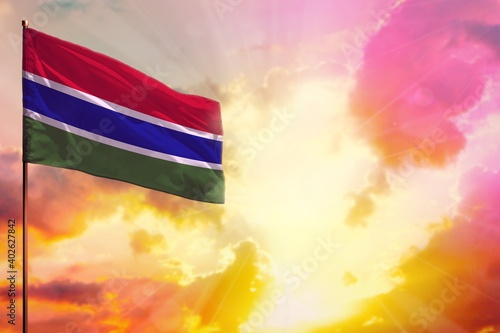 Fluttering Gambia flag in top left corner mockup with the space for your text on beautiful colorful sunset or sunrise background.