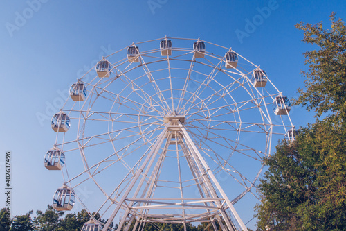 Ferris wheel on the background of the blue sky. Amusement park, fair, no people. Stock photo.