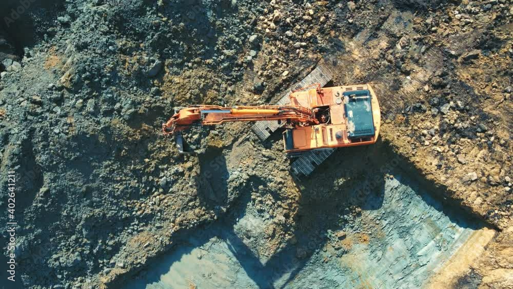 Aerial view on top Excavator that digs and levels the pit for the house. Heavy machinery digs a pit and levels the horizon. Building a house. Aerial view on top Excavator that digs and levels the pit for the house. Heavy machinery digs a pit and levels the horizon. Building a house.