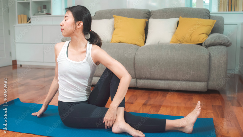 Young Asian woman practicing yoga in living room. Attractive beautiful female working out for healthy at home. Lifestyle woman exercise concept. Young Asian woman practicing yoga in living room. Attractive beautiful female working out for healthy at home. Lifestyle woman exercise concept.