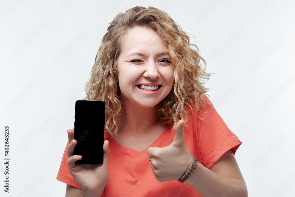 Young laughing woman Showing Smartphone Blank Screen, looking at Camera Recommending Mobile App Young laughing woman Showing Smartphone Blank Screen, looking at Camera Recommending Mobile App