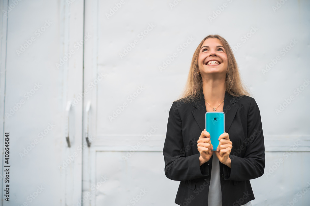 Outdoor portrait of ecstatic modern businesswoman who is holding smartphone. Outdoor portrait of ecstatic modern businesswoman who is holding smartphone.