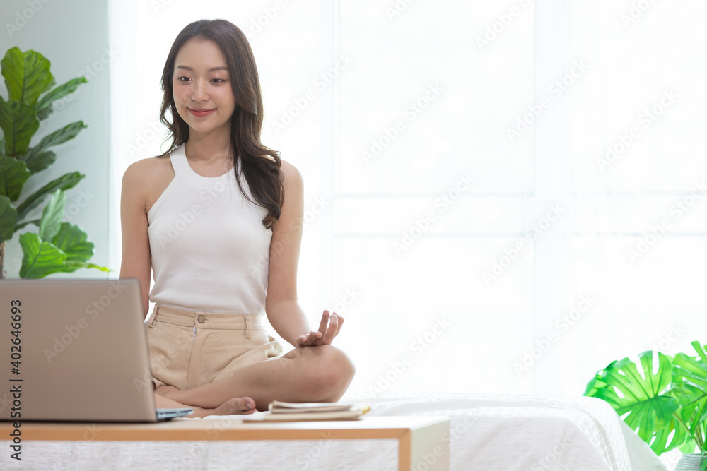 Asian woman play and learn yoga online in labtop at home.