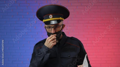 a man in a military uniform of the Russian police with a coronavirus mask checks documents. English translation police, Russia photo