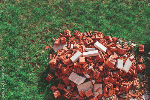 a pile of red broken bricks on a green lawn
