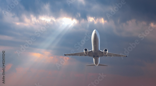 Airplane flying over tropical sea at beautiful light sunset or dramatic sky 