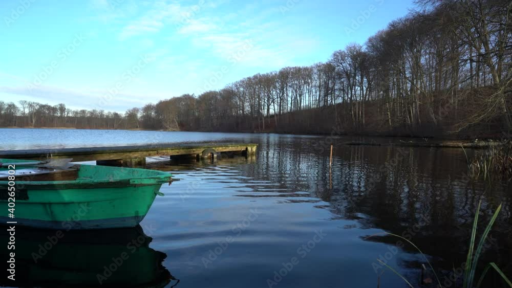 Old green rowing boat moving gently on lake Huwenowsee in winter sunlight Old green rowing boat moving gently on lake Huwenowsee in winter sunlight