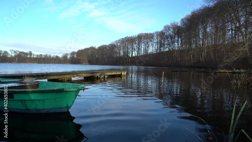 Old green rowing boat moving gently on lake Huwenowsee in winter sunlight