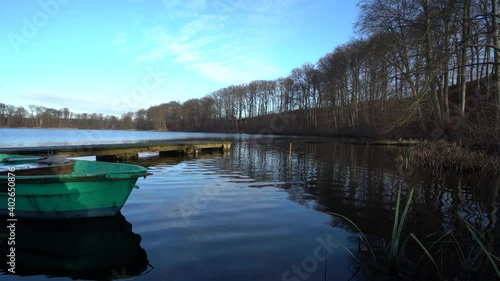 Old green rowing boat moving gently on lake Huwenowsee in winter sunlight