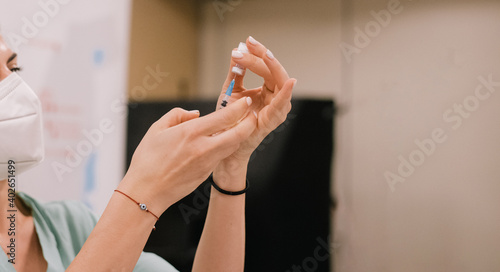 Israel, 29.12.2020 The woman nurse hold in hands antiviral vaccine and syringe against coronavirus with medical protection white mask. All worid make injections for people. pfizer liquid for safe life