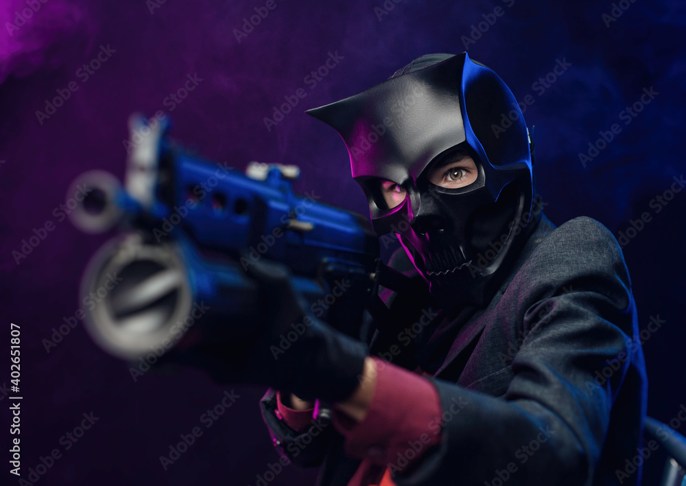 a man wearing a demon skull mask in a leather cloak with an airsoft gun a man wearing a demon skull mask in a leather cloak with an airsoft gun