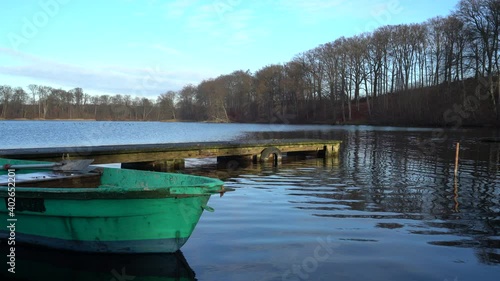 Old green rowing boat moving gently on lake Huwenowsee in winter sunlight