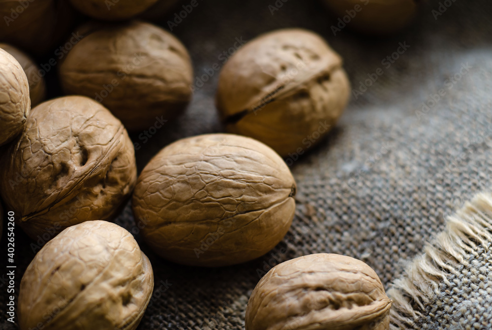 Walnuts lie in heap on gray background of coarse burlap Walnuts lie in heap on gray background of coarse burlap