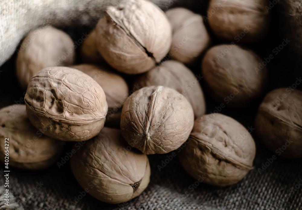 Walnuts lie in  heap on  gray background of coarse burlap