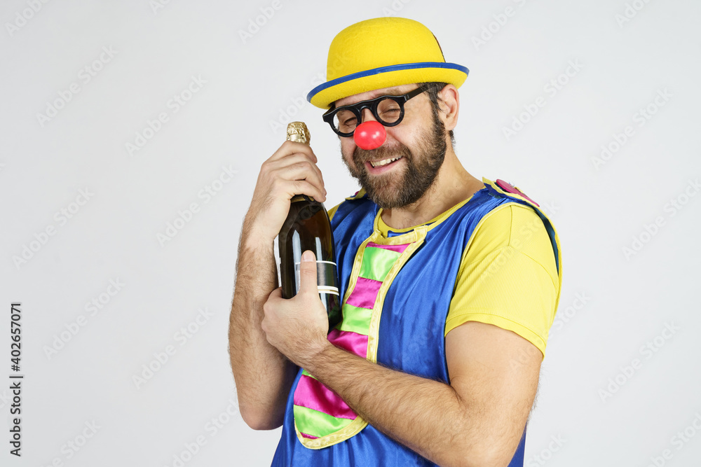 A clown in a bright suit holds a bottle of champagne in his hands