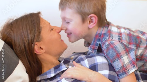 young mom and her son are cuddled and tickled on the sofa at home