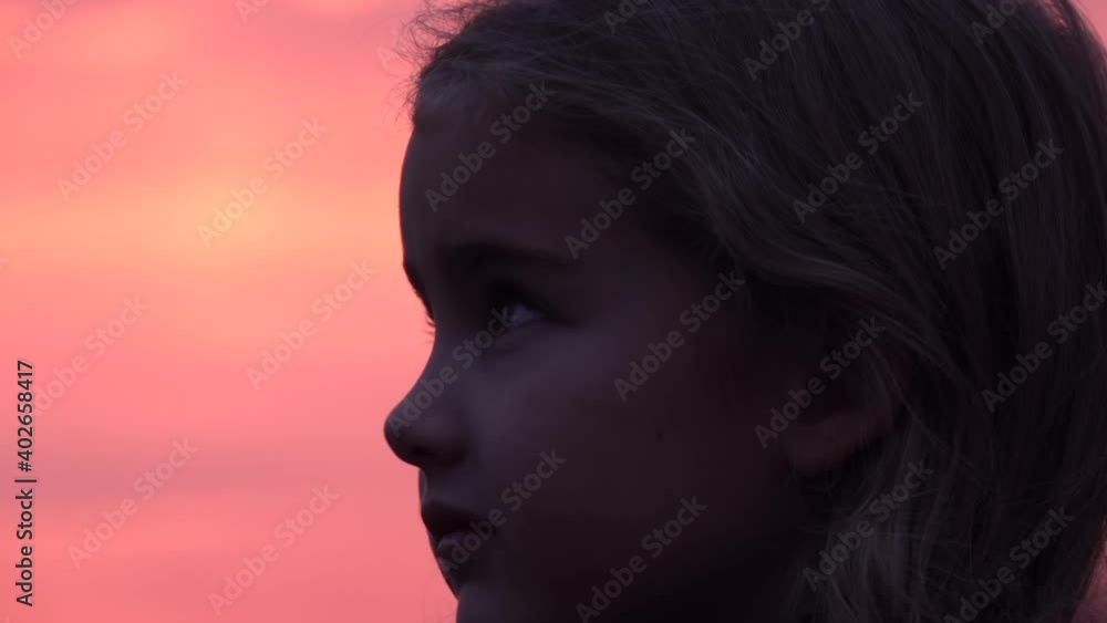 Kid looking up at the sky in nature. Little girl praying looking up at purple sky with hope, close-up. Kid looking up at the sky in nature. Little girl praying looking up at purple sky with hope, close-up.