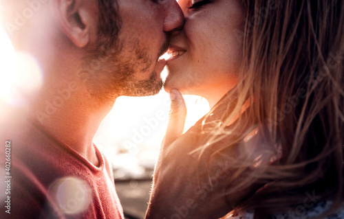 Romantic couple in love kissing at sunset - Boyfriend and girlfriend having a romance kiss outdoor - Warm filter