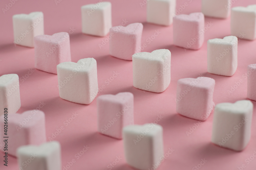 Blurred image of marshmallow hearts standing in rows on a pink background. Blurred image of marshmallow hearts standing in rows on a pink background.