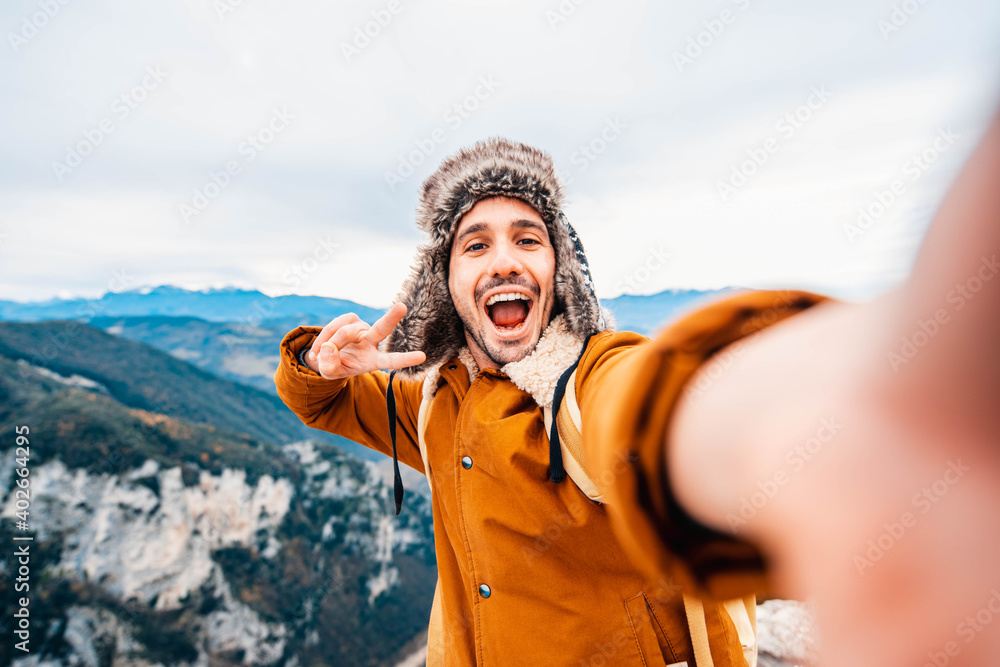 Happy man taking a selfie climbing mountains - Smiling hiker hiking hill - People, technology and sport concept