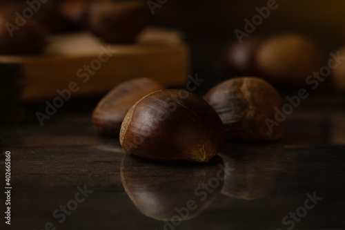 Not roasted fresh chestnuts in a wooden table