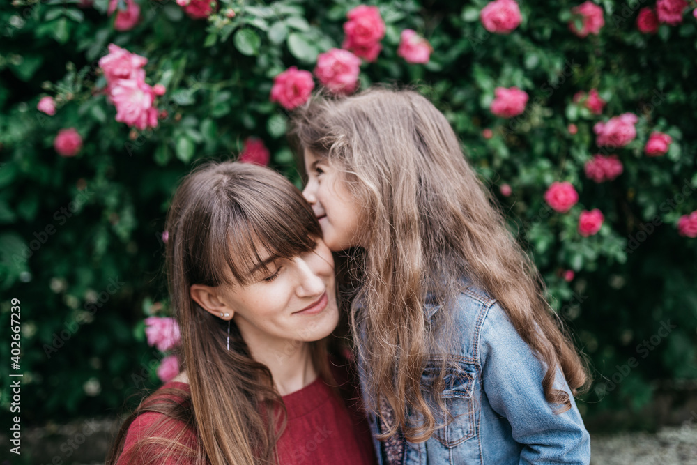 Daughter kisses mom in the spring in the park Daughter kisses mom in the spring in the park