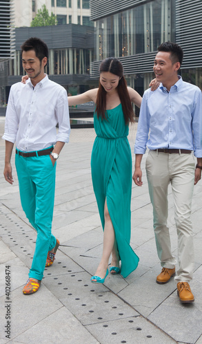 Three young people are chatting and walking outdoors 