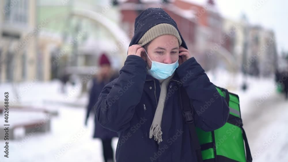 Courier is delivering food with backpack at winter. Courier is delivering food with backpack at winter.