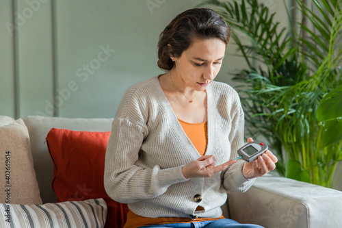 Young woman measures blood sugar level photo