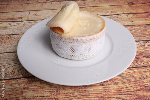 Cheese, Torta del Casar open, on black plate on wooden background top view