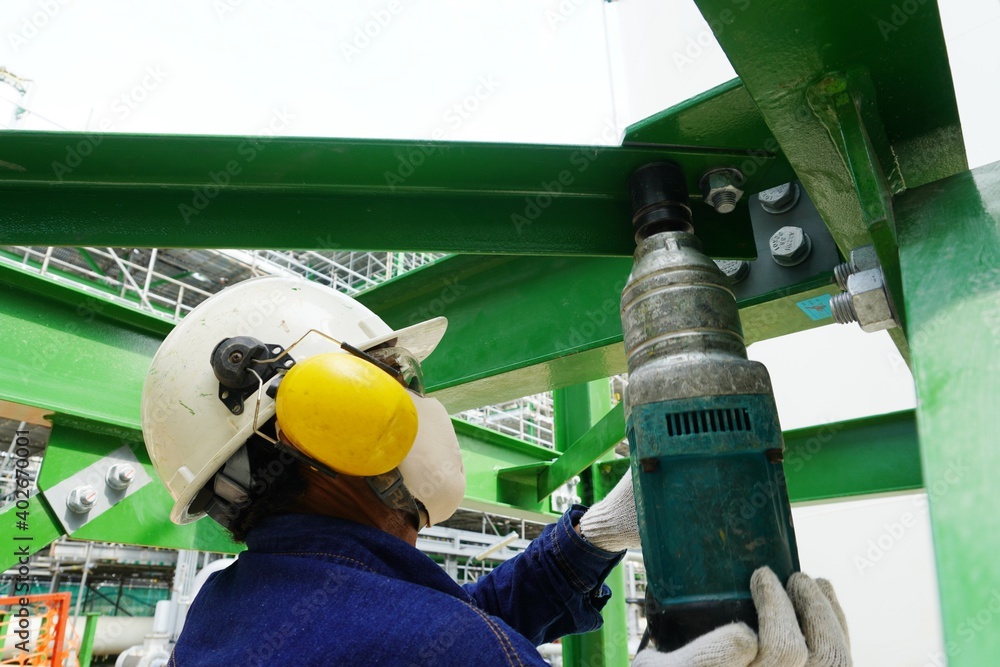 Worker use the power screw driver tighten the steel bolt as part of the