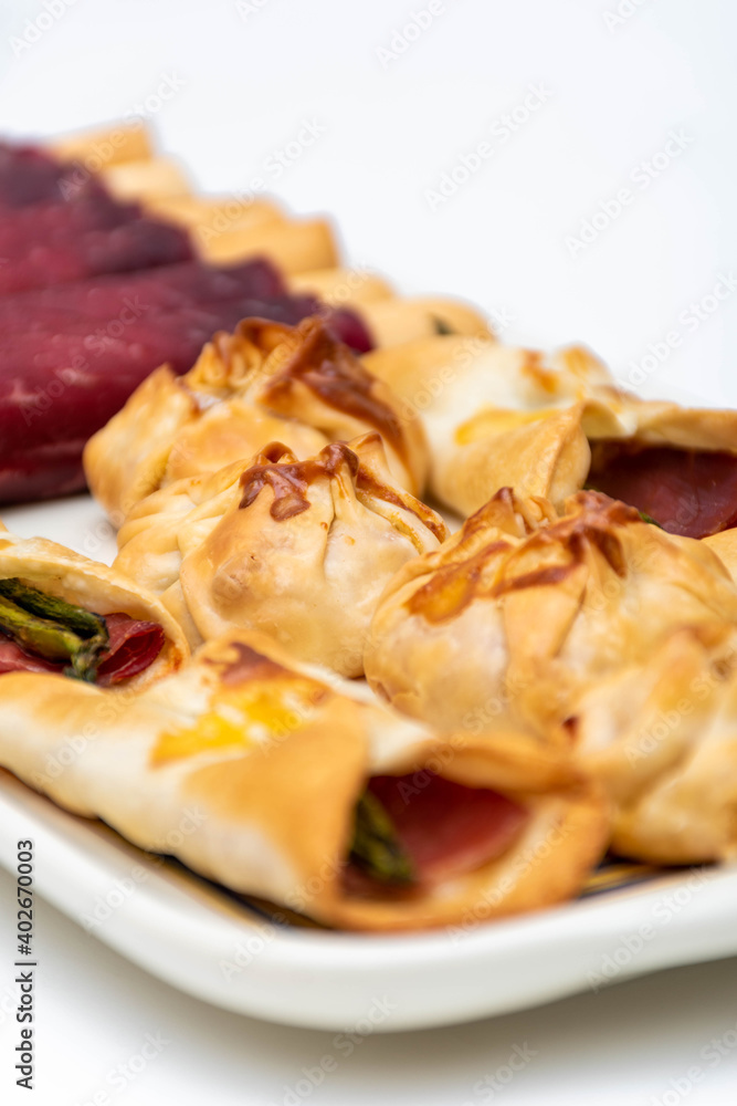 Vertical macro view of canapés and sachets with vegetables and ham and a pair of waiter's tongs. Selective focus Vertical macro view of canapés and sachets with vegetables and ham and a pair of waiter's tongs. Selective focus