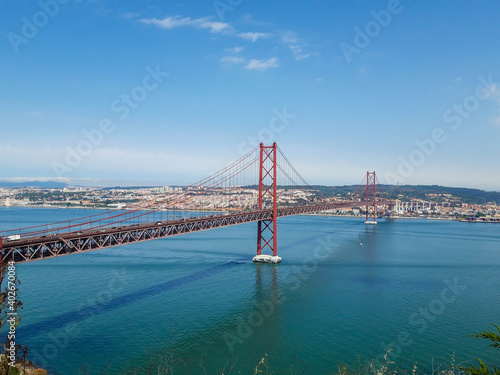 Lisbon's red suspension bridge on a sunny day with the city in the background