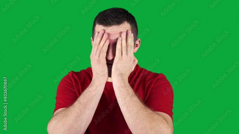 man covering his eyes with his hands on a green screen. man covering his eyes with his hands on a green screen.