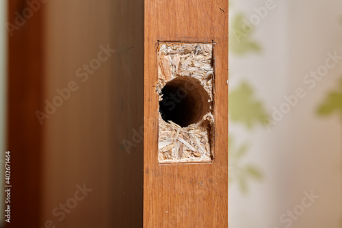 A hole for a door lock latch and a rectangle, hollowed out by a chisel for a plate in a chipboard panel.