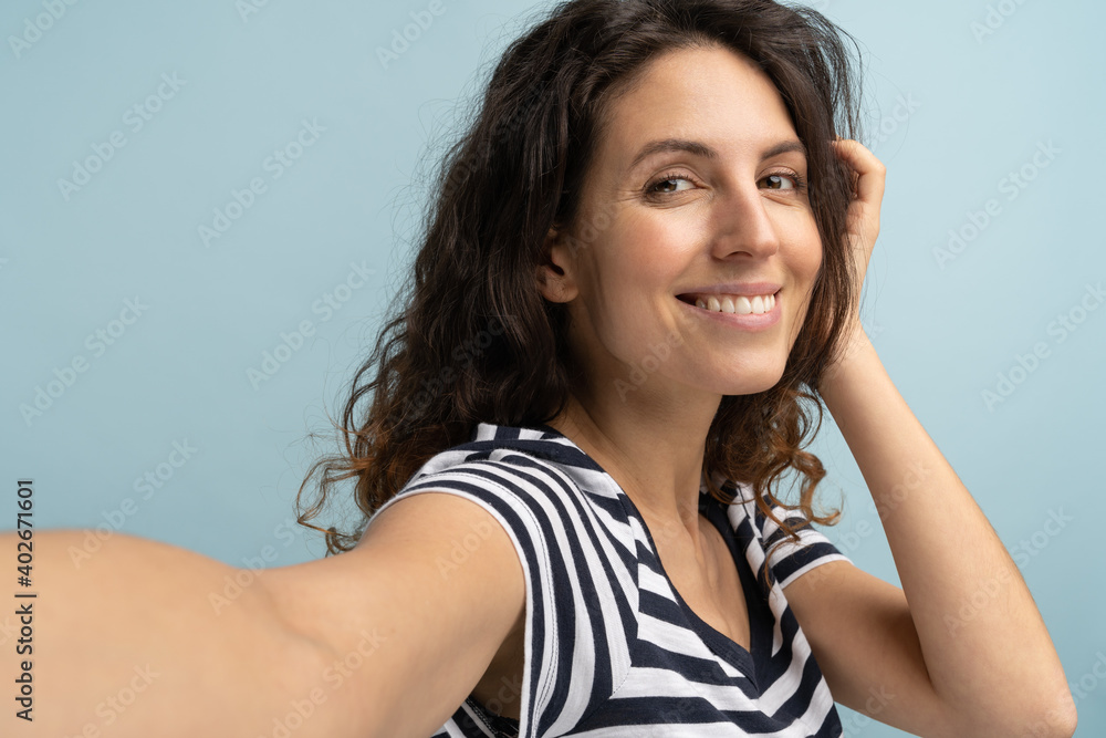 Woman having cheerful expression making selfie, stretching arm to camera, photographing herself Woman having cheerful expression making selfie, stretching arm to camera, photographing herself